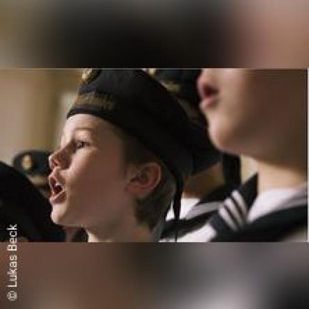 Ein Junge in Marineuniform singt.