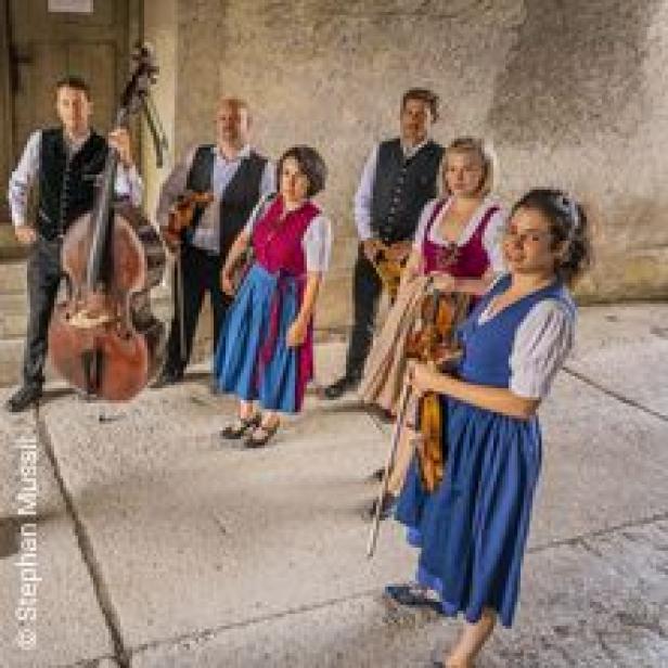 Eine Gruppe von Musikern in Tracht posiert mit ihren Instrumenten.
