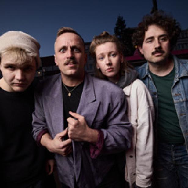 Eine Gruppe von vier jungen Erwachsenen posiert für ein Foto im Freien.