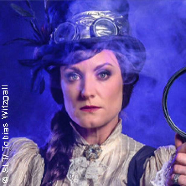 Eine Frau im Steampunk-Stil mit Zylinder und Lupe vor blauem Hintergrund.