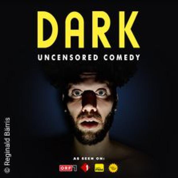 Ein Mann mit dunklem Haar und Bart, der überrascht in die Kamera schaut, bewirbt „Dark Uncensored Comedy“.