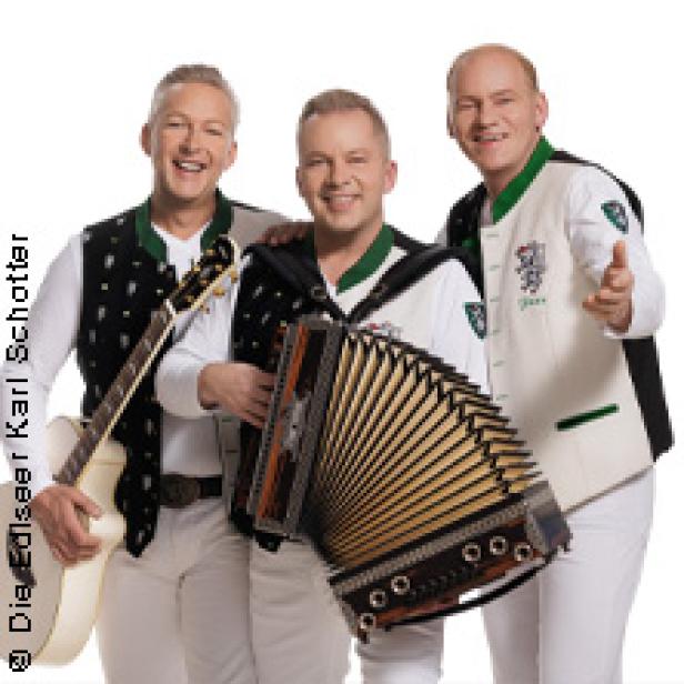 Die Edlseer posieren mit Gitarre und Akkordeon vor einem weißen Hintergrund.