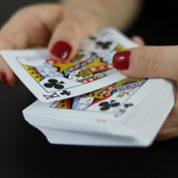 Eine Person mischt einen Stapel Spielkarten.