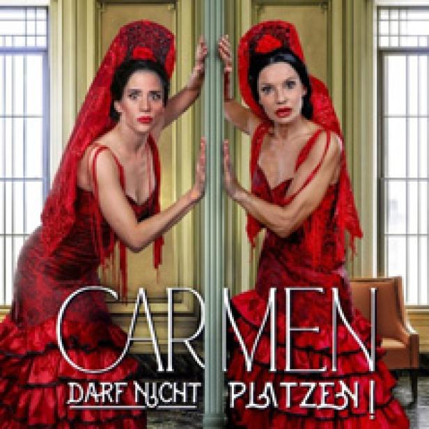 Zwei Frauen in roten Flamenco-Kleidern stehen an einem Spiegel, mit dem Titel „Carmen darf nicht platzen!“.