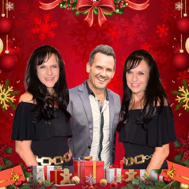 Ein Mann steht zwischen zwei Frauen vor einem weihnachtlichen Hintergrund.