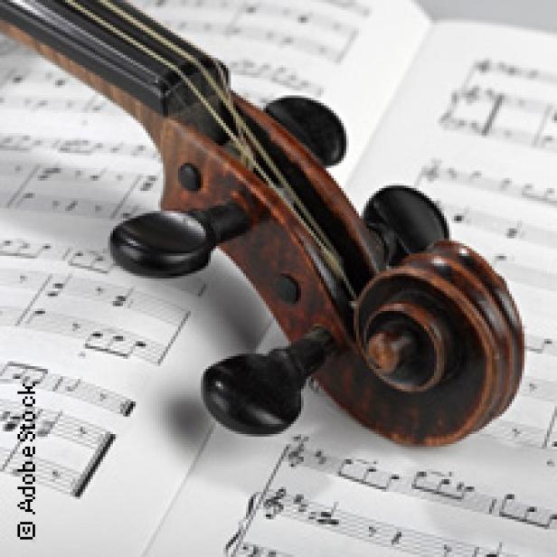 Der Kopf einer Geige liegt auf Notenblättern.