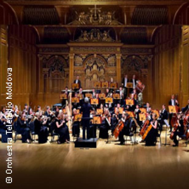 Ein Orchester spielt in einem reich verzierten Konzertsaal.