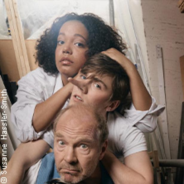 Drei Personen posieren für ein Foto, wobei die mittlere Person eine lange Nase hat.