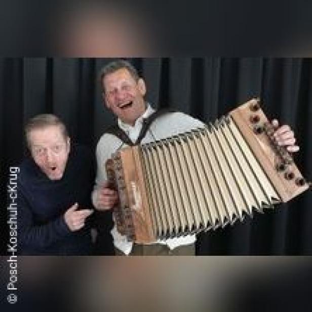 Zwei Männer posieren mit einer Steirischen Harmonika vor einem schwarzen Vorhang.
