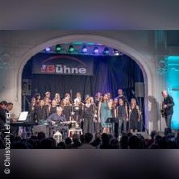 Ein Chor tritt auf einer Bühne vor Publikum auf.